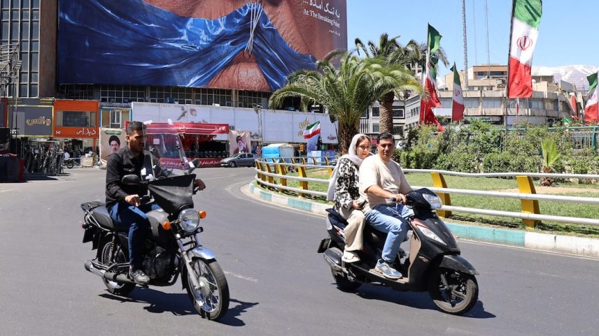 Motoristas passam, neste domingo, 10, por um outdoor antiamericano que faz referência ao presidente Donald Trump e ao Estreito de Ormuz, instalado em um prédio na Praça Valiasr, em Teerã.