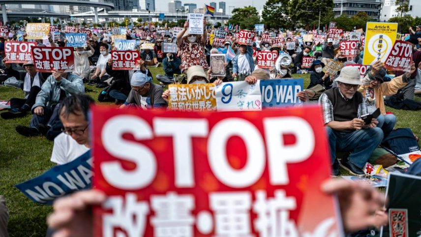 Pessoas seguram cartazes com os dizeres “Não à guerra” e “Parem a revisão constitucional e a expansão militar” durante a Grande Manifestação pela Constituição de 2026, em comemoração ao Dia da Constituição, em Tóquio, em 3 de maio de 2026