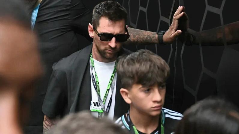 Lionel Messi deixa os boxes da Mercedes acompanhado do filho (Foto: CHANDAN KHANNA / AFP)