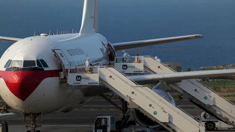 Um evacuado espanhol, vestindo um traje de proteção branco, embarca pela porta traseira de um Airbus A310 da Força Aérea Espanhola no aeroporto de Tenerife - (Antonio Sempere/AFP)