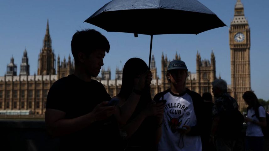 Grupo se protege do sol com um guarda-chuva em Londres, na Inglaterra, durante a intensa onda de calor que atinge a Europa Ocidental, em 26 de maio de 2026