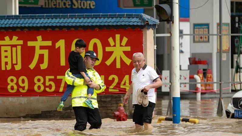A police officer holds a boy as he wades through a flooded street in Duyun city, southwestern China’s Guizhou Province on Tuesday, May 19, 2026. Image by Xiao Wei/Xinhua via Associated Press.