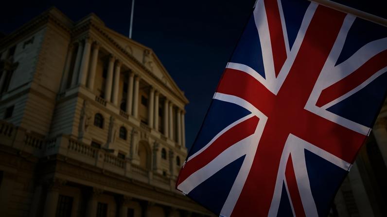 Bandeira do Reino Unido em destaque e o prédio do Banco da Inglaterra em desfoque ao fundo