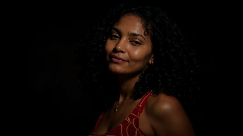 Foto de uma mulher negra, do cabelo preto e cacheado, usando uma regata vermelha - Metrópoles