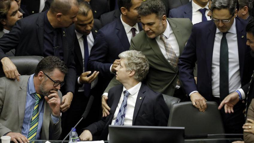 A imagem mostra o deputado Marcel Van Hatten (ao centro) sentado em uma das cadeiras da Mesa Diretora durante a ocupação do local por congressistas bolsonaristas em 2025