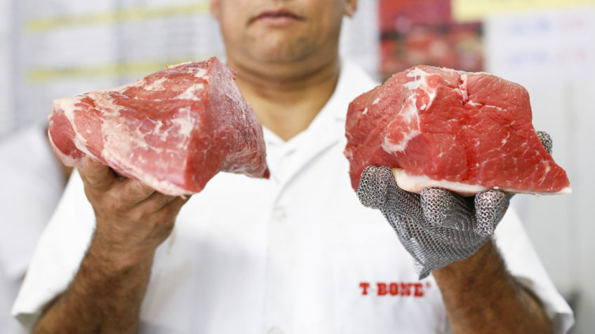 O setor de atacarejo, que atende principalmente consumidores de menor poder aquisitivo e funciona como indicador do consumo alimentar, já observa mudanças no padrão de compras; na imagem, açougueiro segura pedaços de carne