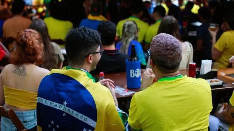 Não se pode tratar a publicidade de apostas como ameaça existencial e a publicidade de álcool como paisagem cultural da Copa, diz o articulista; na imagem, brasileiros acompanham jogo da seleção em bar de Brasília, em dezembro de 2022