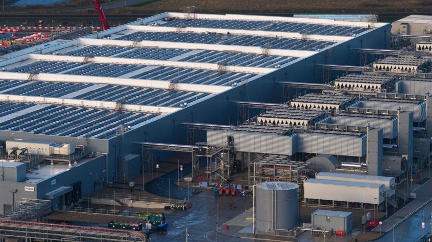 Aerial drone video of a large data center building exterior representing the massive technological infrastructure...