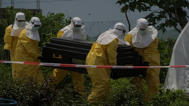 Em 20 de maio, funcionários da Cruz Vermelha carregam o caixão de uma pessoa que morreu de Ebola em um centro de saúde em Rwampara, República Democrática do Congo