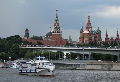 Embarcação navega pelo rio Moscou com a Torre Spasskaya do Kremlin e a Catedral de São Basílio ao fundo - 14 de julho de 2025