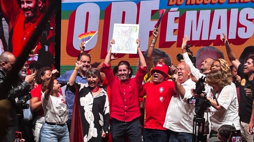 Ao centro da imagem, o pré-candidato ao governo do DF, Leandro Grass, levanta um cartaz; à esquerda de Grass na foto, a pré-candidata ao Senado Erika Kokay