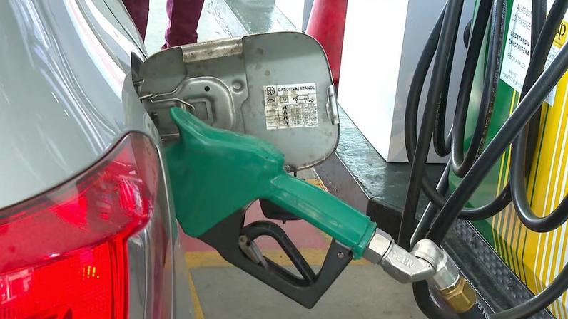 Em um posto de gasolina, um carro estacionado ao lado de uma bomba do local reabastece o próprio tanque.