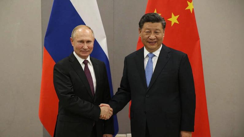 Imagem colorida mostra Vladimir Putin e Xi Jiping apertando as mãos - Metrópoles