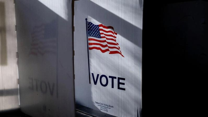 An American Flag and the word vote printed on a voting booth