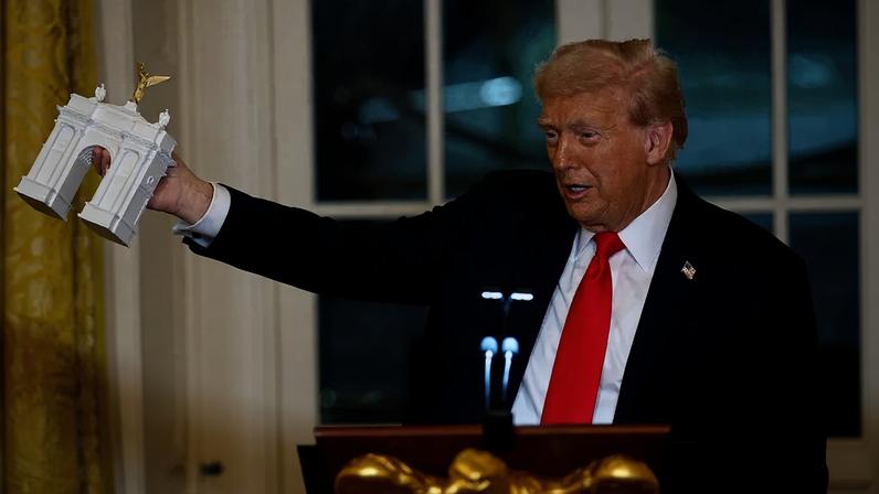 President Donald Trump holds up a model of his proposed Memorial Circle arch in Washington, D.C.