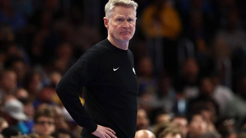 Golden State Warriors coach Steve Kerr rests his hands on his hips while watching a game from the sideline.