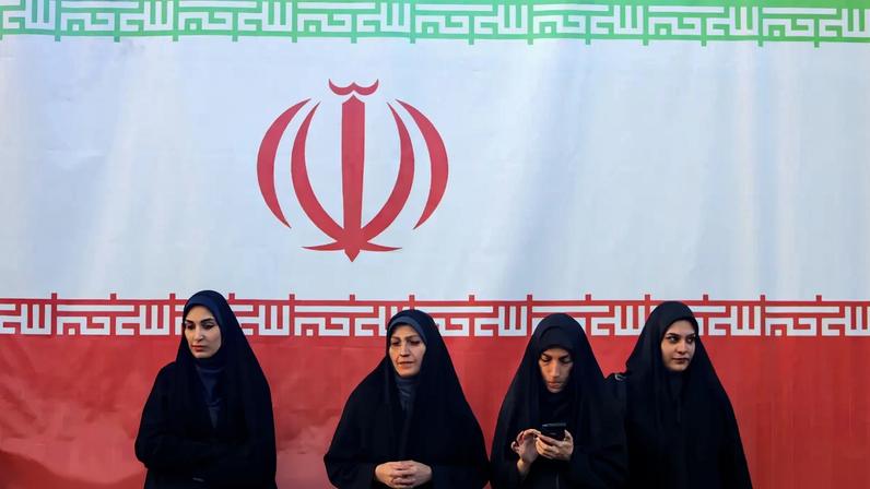 Mulheres em frente a uma bandeira iraniana no dia 17 de abril de 2026, em Teerã, Irã