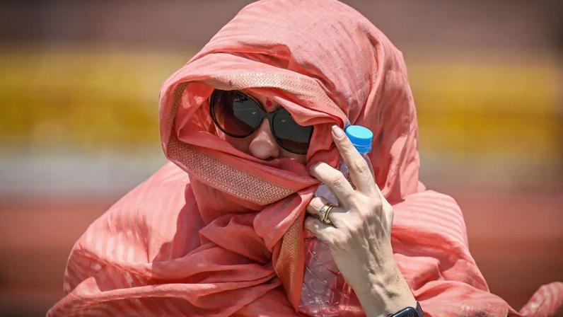 Mulher tenta proteger o rosto do calor extremo que atinge Nova Délhi, capital da Índia, em maio de 2026