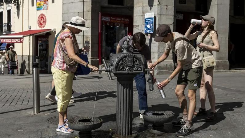 Pessoas bebem água de fonte na Plaza Mayor durante uma onda de calor em Madrid, na Espanha. 23/05/2026