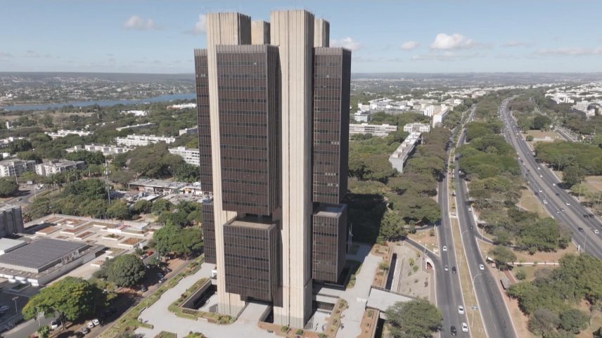 Vista aérea do edifício do Banco Central do Brasil em Brasília, com avenida e áreas verdes ao redor