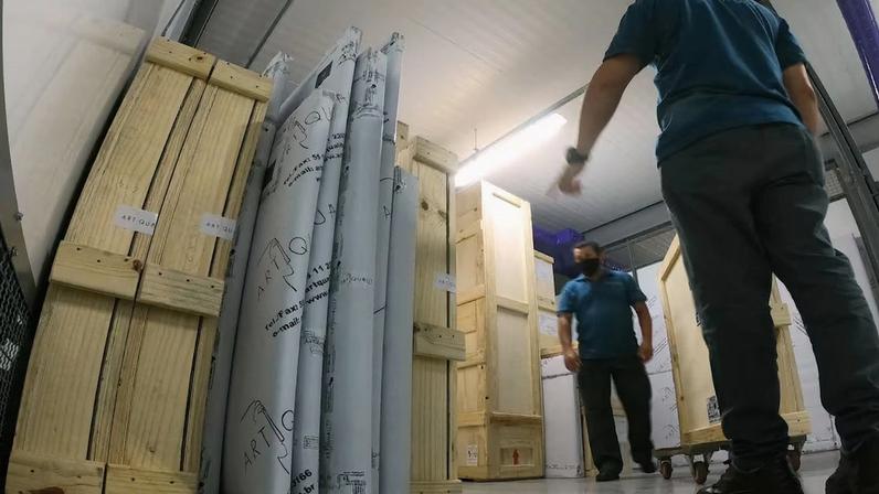 Funcionários movimentam embalagens com obras de arte em reserva técnica da Clé Chenue do Brasil em São Paulo.