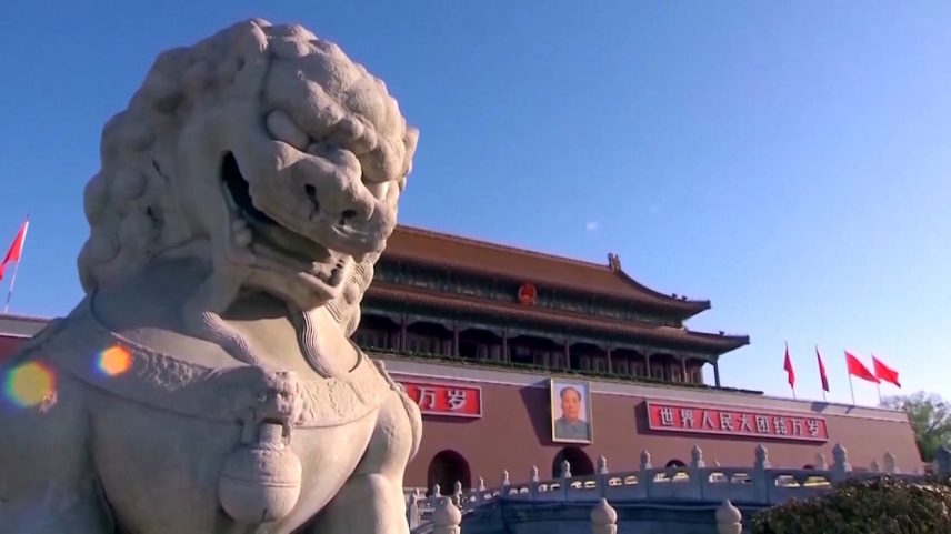 Estátua de pedra diante de um edifício histórico com bandeiras vermelhas na China