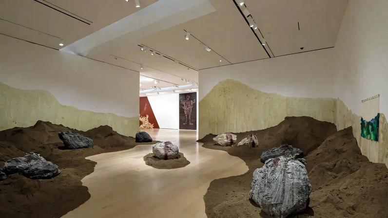 View of a museum with a mounds of soil lining the walls creating a path to the next gallery.