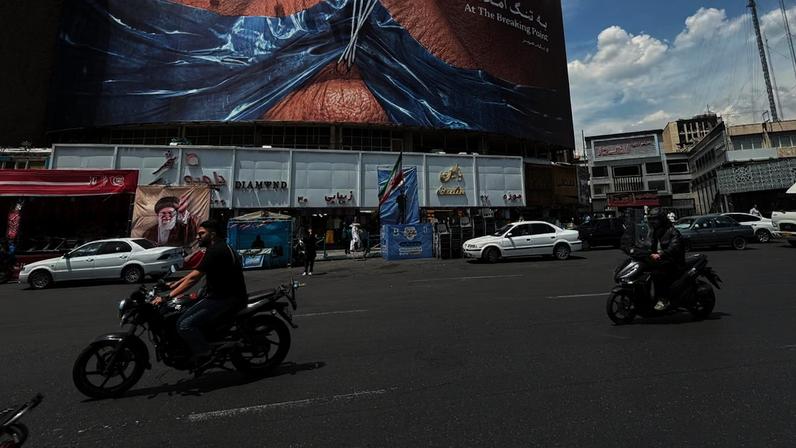No centro de Teerã, publicidade mostra Donald Trump com a boca tapada por fita adesiva no formato do estreito de Ormuz.VehÃ­culos circulan junto a una valla publicitaria con una imagen del estrecho de Ormuz y los labios cosidos del presidente estadounidense Donald Trump, en una plaza del centro de TeherÃ¡n, IrÃ¡n, el sÃ¡bado 2 de mayo de 2026. (Foto AP/Vahid Salemi)
