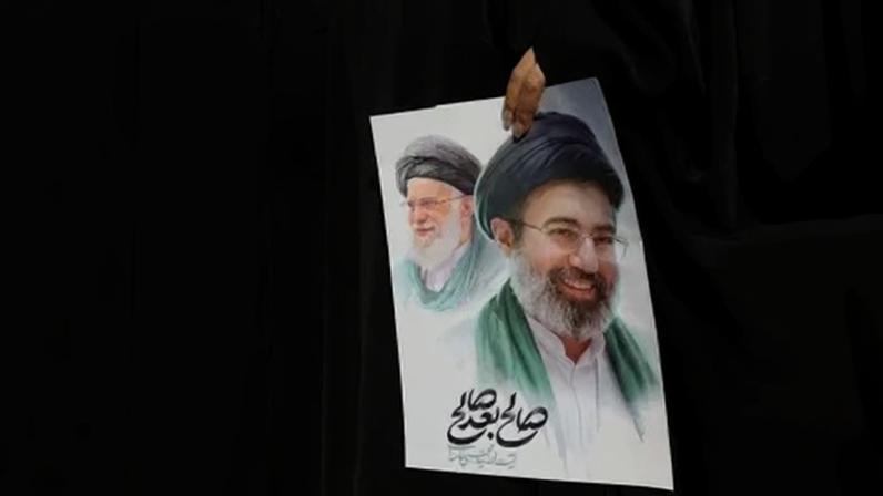 Mulher segura imagem do novo líder supremo do Irã, Mojtaba Khamenei, e do líder anterior, o aiatolá Ali Khamenei, durante cerimônia fúnebre para comandantes militares iranianos 11 de março de 2026