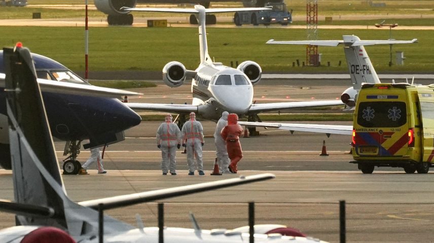 A person in a hazmat suit is escorted to a ambulance from a medical aircraft allegedly carrying some of the passengers...