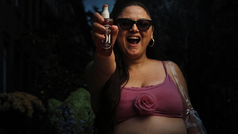 Actress Meg Statler sprays a bottle of body mist into the camera in a campaign for Sol de Janeiro.