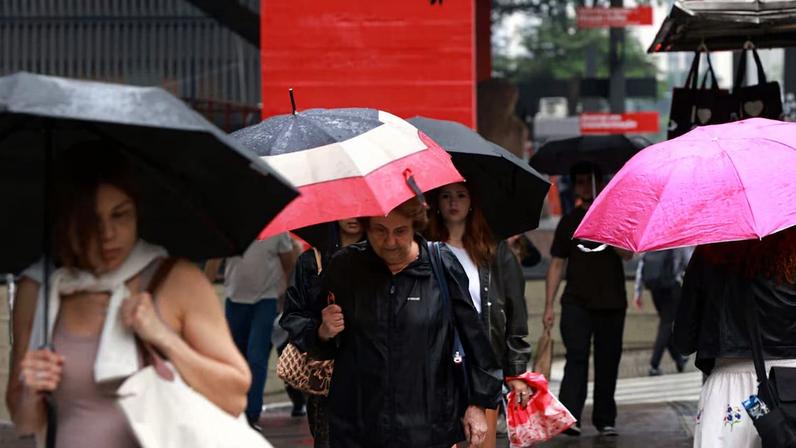 Pedestres caminham com guarda-chuva na Av. Paulista