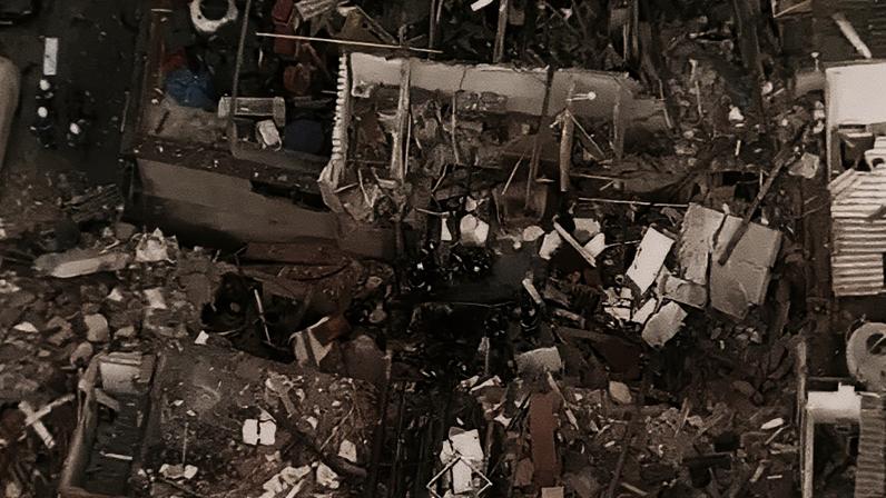 Vista aérea de prédio destruído, com escombros espalhados e estruturas colapsadas