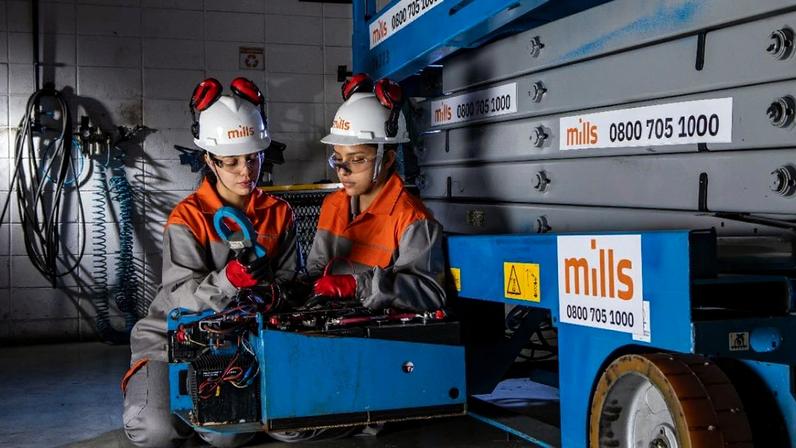 Duas pessoas com EPIs trabalhando na manutenção de uma plataforma elevatória azul da Mills.