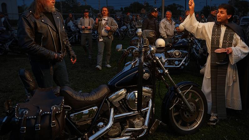 A Catholic priest sprinkles Holy Water on a biker on March 11, 1999, during the annual “Blessing of the Bikes” on the last day of Bike Week in Daytona Beach, Florida.
