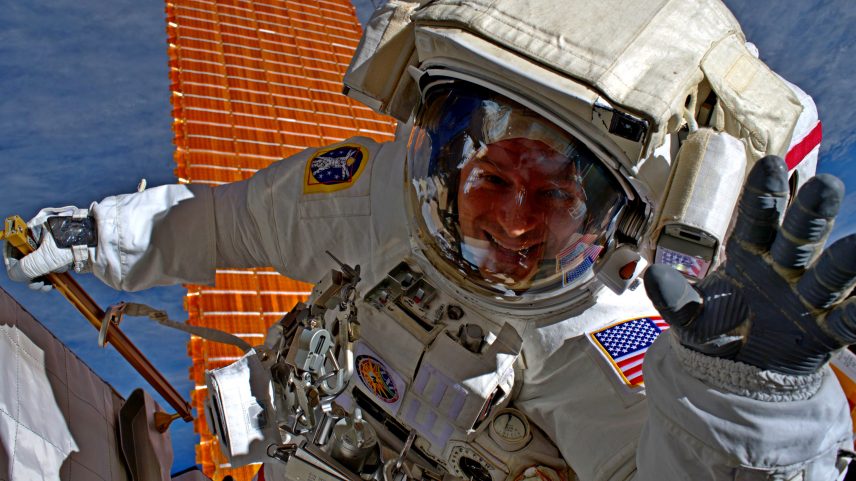Former NASA astronaut Andrew Morgan waves as he is photographed during an Expedition 61 spacewalk outside the International Space Station.