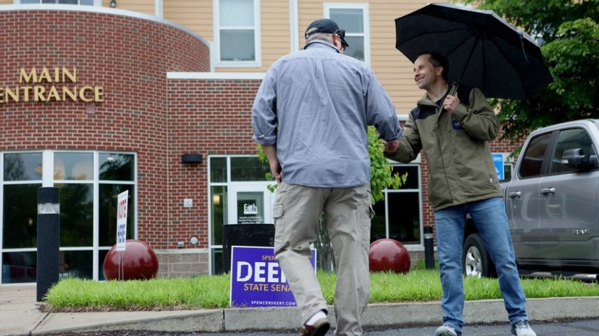 Senador estadual Spencer Deery, republicano (casaco verde) cumprimenta eleitor em West Lafayette; ele foi o único dos oponentes de Trump no estado a vencer