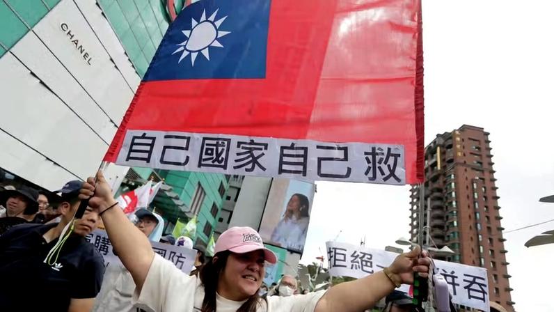 Uma mulher segura a bandeira de Taiwan com um slogan que diz: 'Salvem nosso próprio país!' em Taipei, Taiwan, sábado, 23 de maio de 2026.