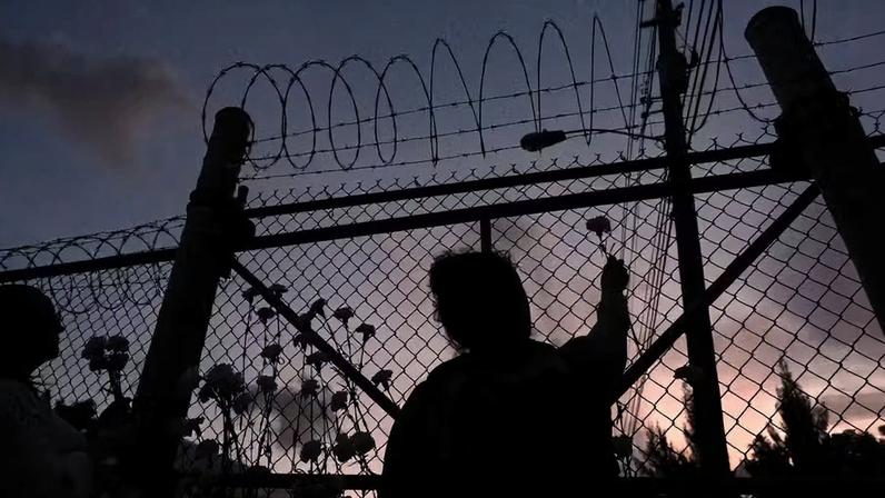 Pessoas depositam flores em uma cerca do lado de fora do Centro de Detenção de Krome, em Miami, no sábado, 24 de maio de 2025, durante uma vigília em homenagem às pessoas que morreram sob custódia do Serviço de Imigração e Alfândegas dos EUA (ICE), bem como àquelas afetadas por deportações em massa