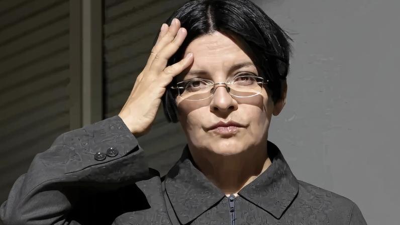 A woman in glasses shifting her hair.