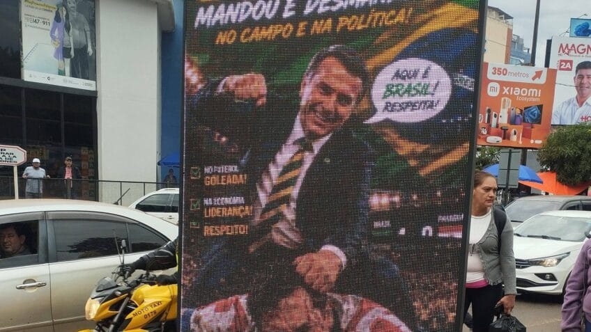 Na foto, o painel publicitário com a montagem de Bolsonaro agredindo jogador com a camisa da seleção paraguaia