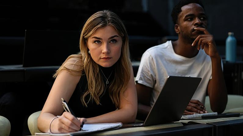Getty Images A stock photo of students in a classroom, with one woman jotting in her notepad