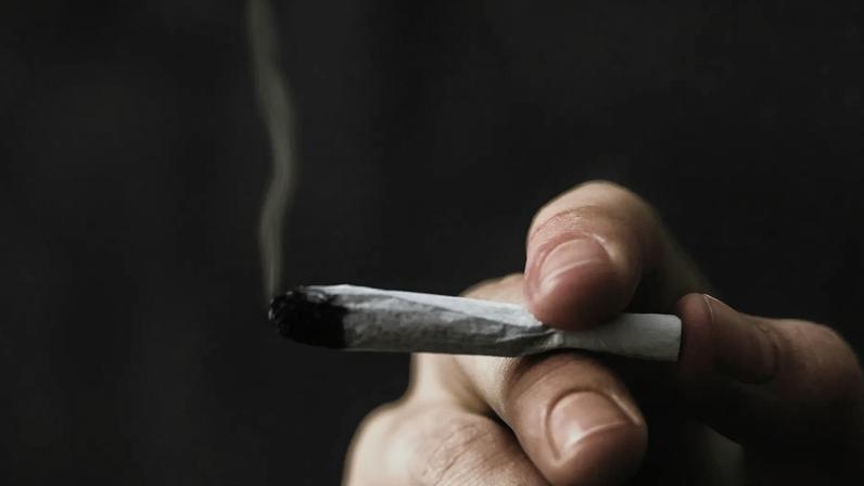 A hand holding a marijuana joint.