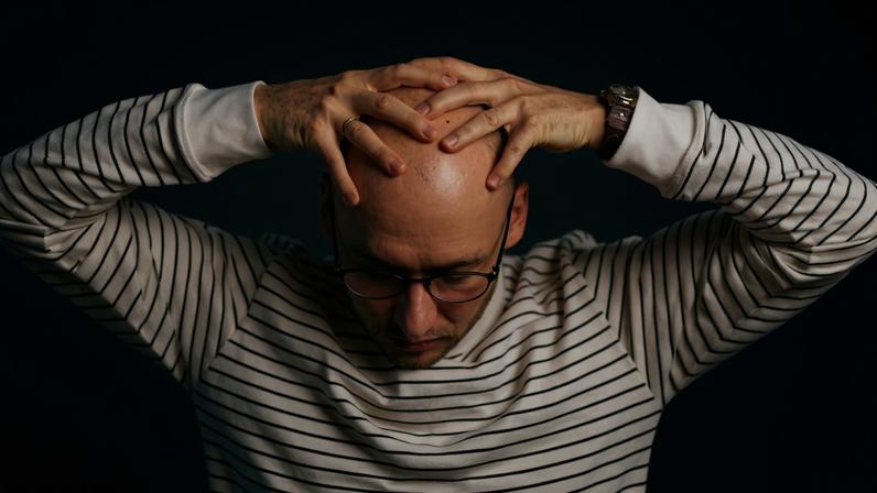 Homem careca com as mãos na cabeça