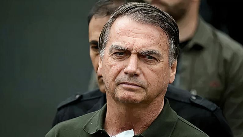 Getty Images Police escort Jair Bolsonaro, who wears a green polo top, from hospital