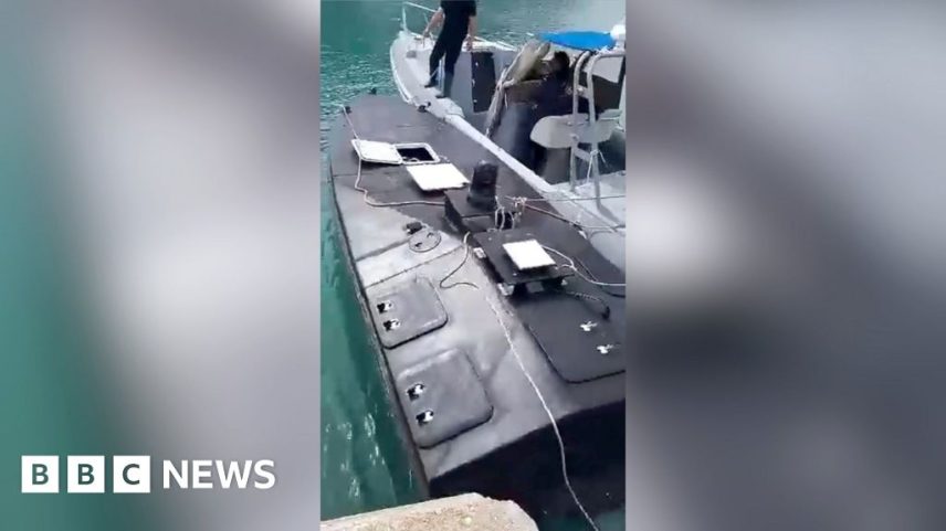 Moment discovered naval drone (left) is towed by a Greek coastguard boat to the port of Vasiliki