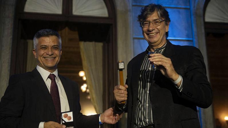 Marcone da Silva Leal, da Casa Moeda (à esquerda) e o Presidente do IBGE, Marcio Pochmann segurando a medalha comemorativa após duas marteladas. Foto: CDDI/CCS/IBGE