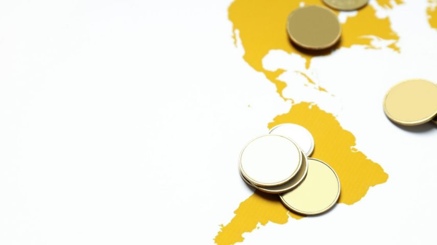 Moedas douradas genéricas sobre um mapa amarelo das Américas.