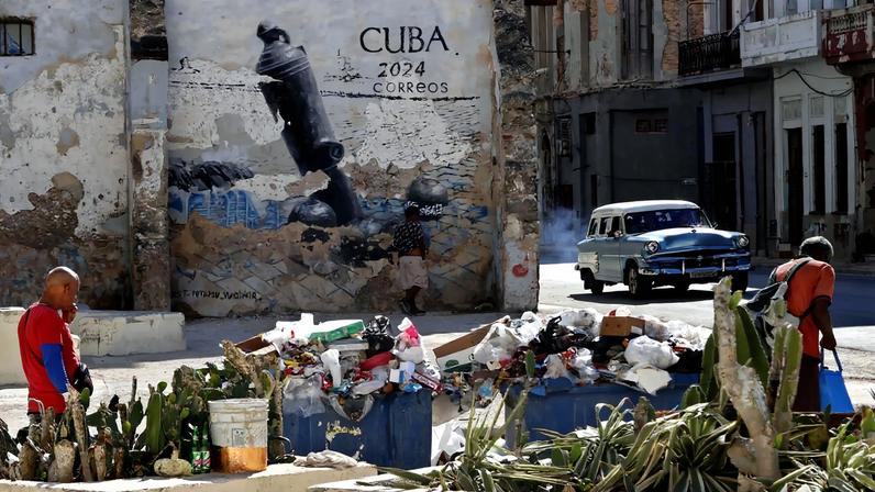 Pessoas caminhando em frente a lixo acumulado em Cuba. (Foto: Ernesto Mastrascusa/EFE)