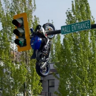 Motocicleta fica pendurada em farol após colisão com carro
